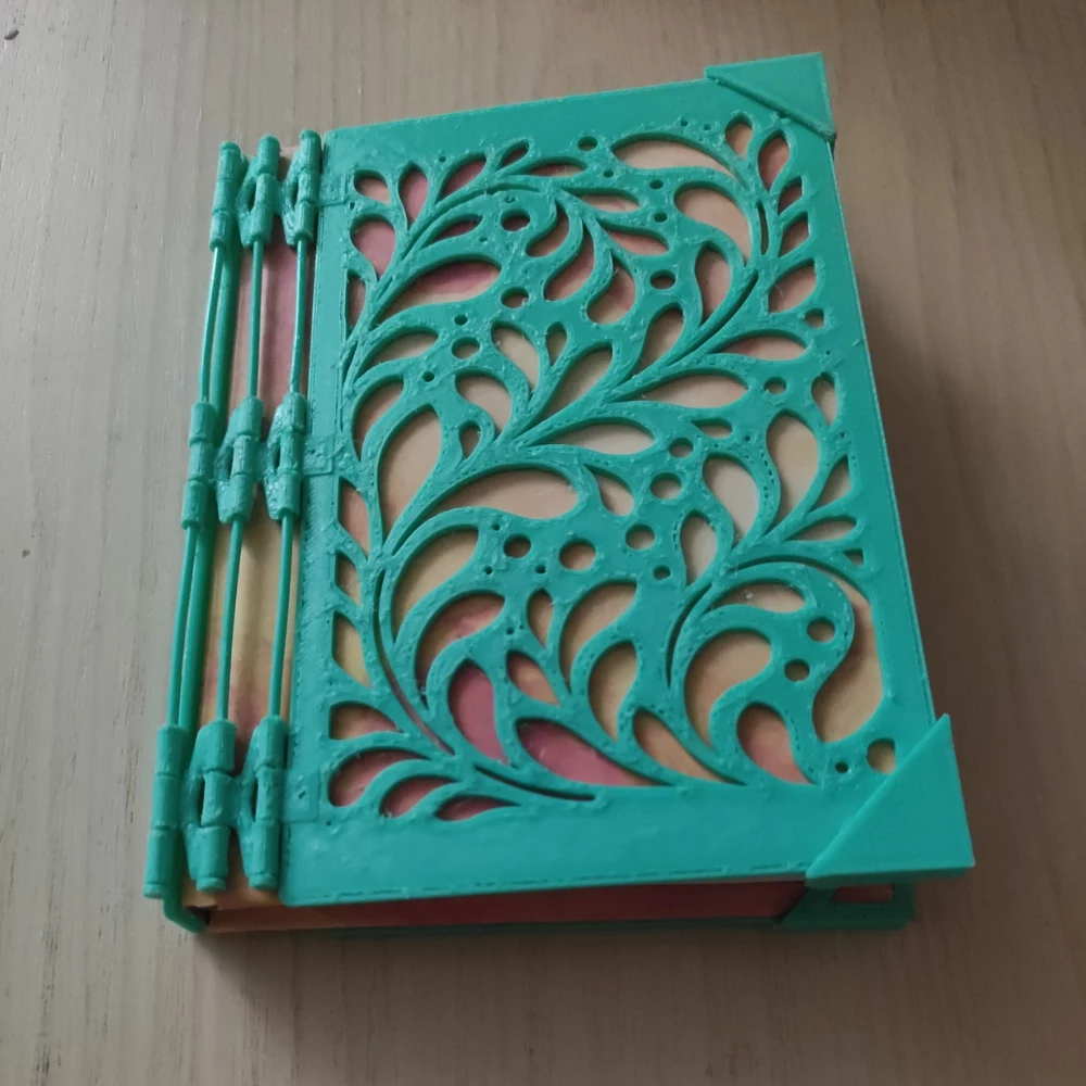 Finished turquoise 3D-printed CoverForge notebook cover fitted to a real notebook