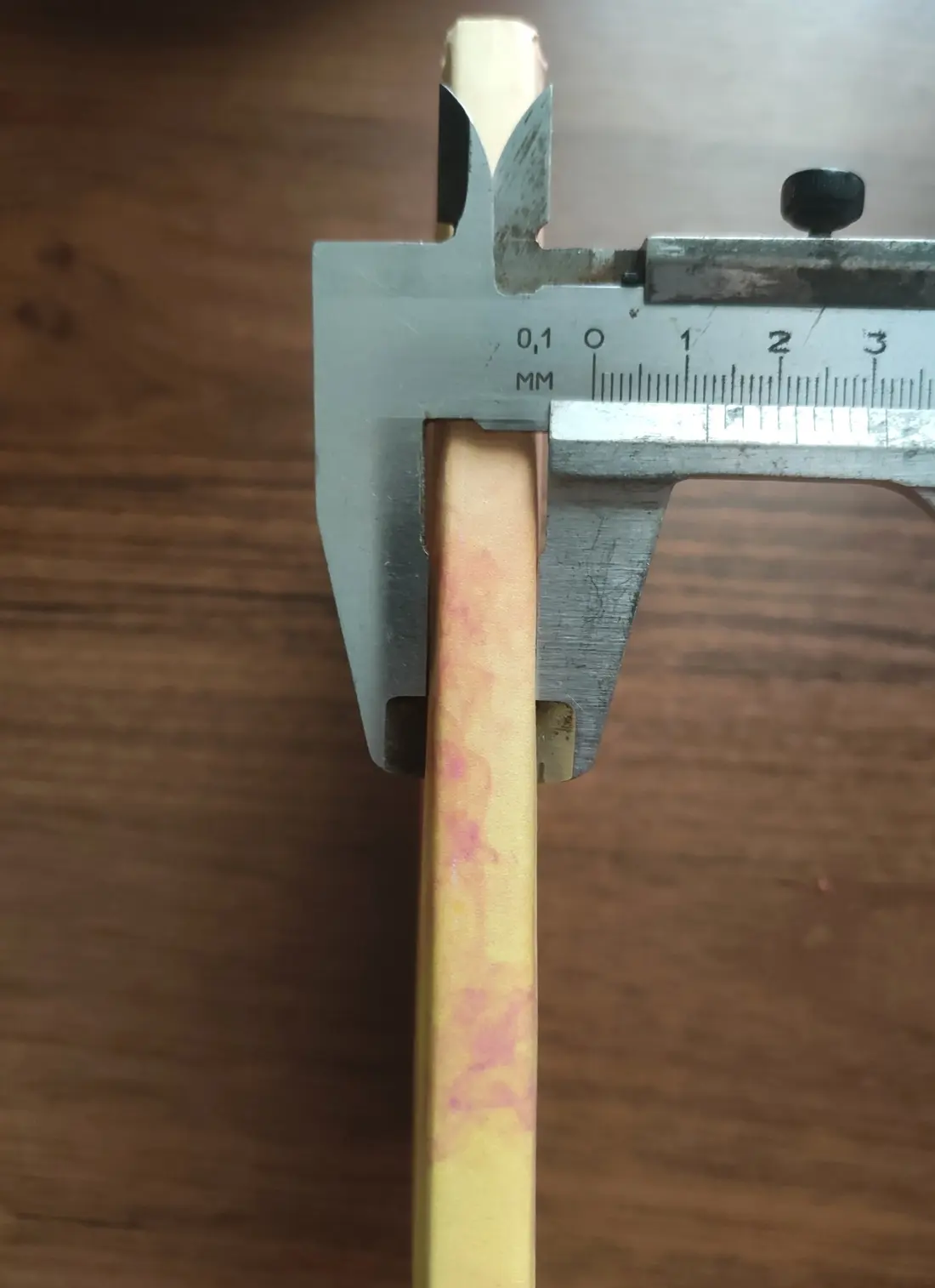 Calipers measuring 12 millimeters between the outside faces of the closed notebook covers at the spine