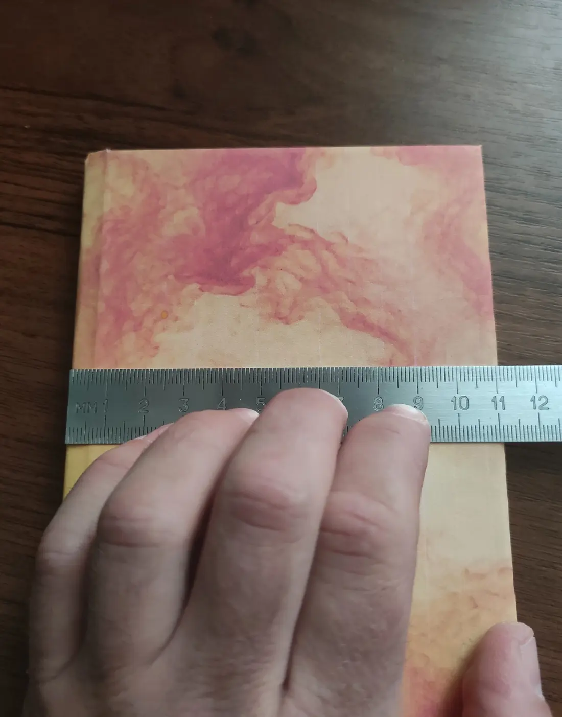 Ruler measuring one closed notebook cover from spine edge to outer edge at 111 millimeters